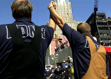 Two heroes raise their arms in prayer as they view the cross