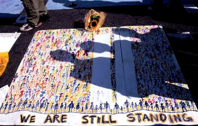 We Are Still Standing: A poster indicates a great truth of 911 - the buildings may be down but WE are not. We stand united, forever. God Bless America.