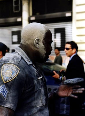 An exhausted hero police officer emerges from Ground Zero covered in dust